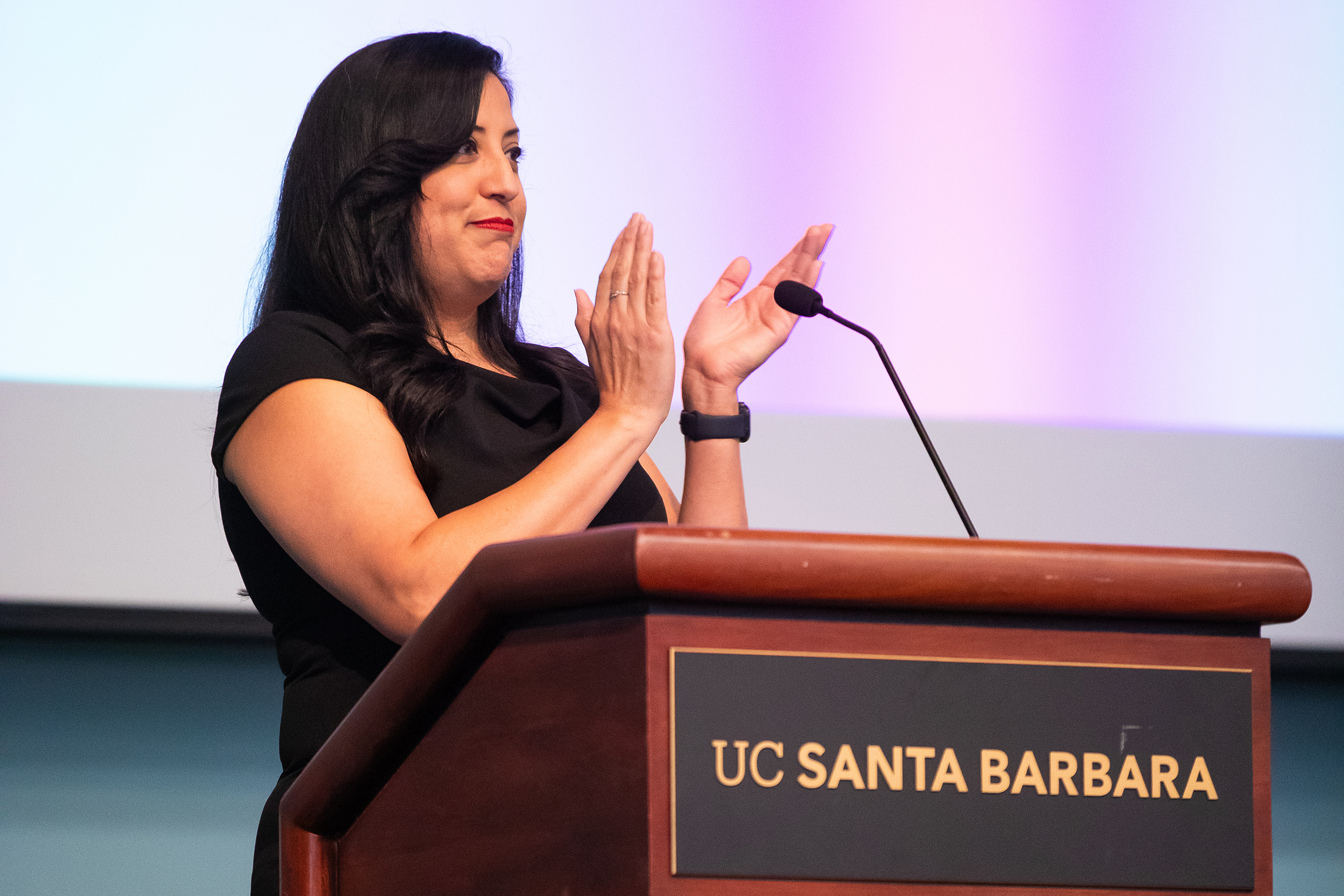 person standing at a podium clapping